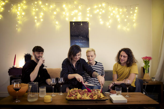 flera personer sitter i en soffa och har plockmat framför sig