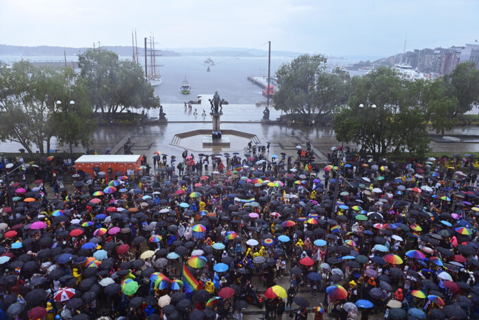 Bild av minnestund med många människor som håller färgglada paraplyer.